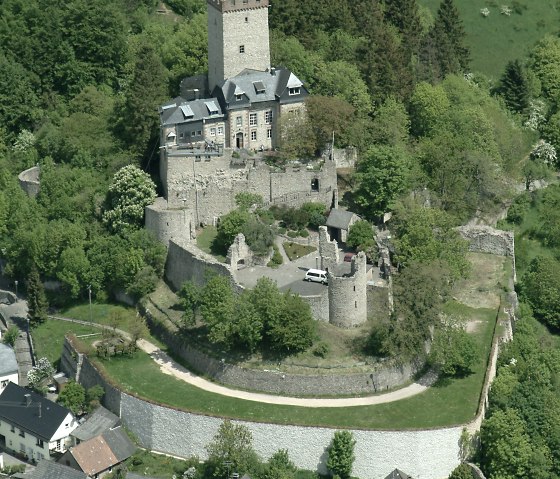 Aerial view of Kerpen Castle, surrounded by green countryside and a small village. The castle has a high tower and is surrounded by trees. Aerial view of Kerpen Castle, surrounded by green countryside and a small village. The castle has a high tower and is surrounded by trees.
