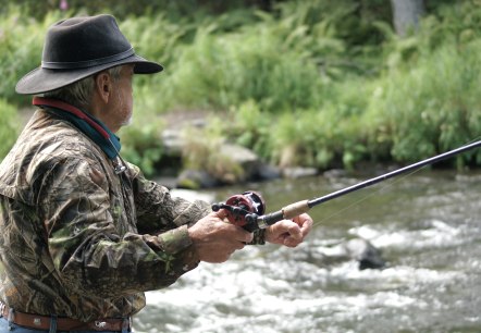 Man fishing
, © Canva A man in camouflage clothing and a fishing hat stands by or in a river and casts his line.