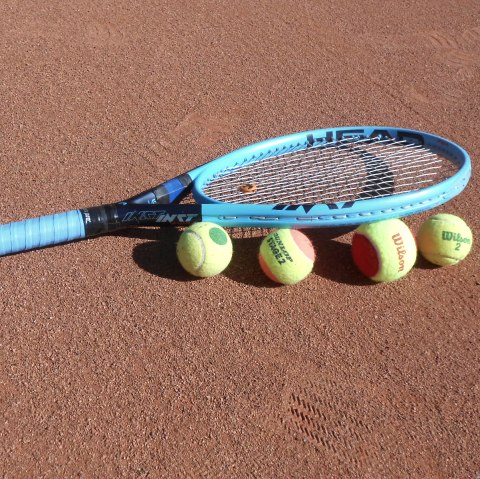 Tennisschläger und -bälle auf einem Tennisplatz.
, © Tennis Club Gerolstein, Bernd May Ein  blauer Tennisschläger liegt auf und neben 4 Tennisbällen auf einem Tennisplatz.