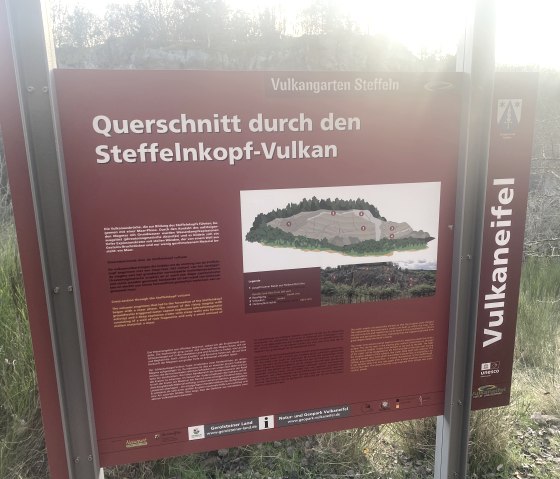 Informationstafel im Vulkangarten Steffeln zum Thema "Querschnitt durch den Steffelnkopf-Vulkan".
, © Touristik GmbH Gerolsteiner Land Informationstafel der Vulkaneifel zum Thema "Querschnitt durch den Steffelnkopf-Vulkan" mit mehrsprachigen Texten und anschaulichen Grafiken.