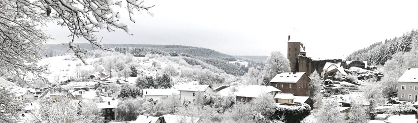 Bertradaburg Mürlenbach im Winter, © Frau Dr. Manuela Wulfert Blick auf eine verschneites Dorf. Eine große Burg ragt zwischen den mit Schnee bedeckten Häusern hervor.
