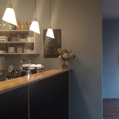 Eingangsbereich Eifel-Film-Bühne Hillesheim
, © Familie Runge Eingangsbereich der Eifel-Film-Bühne in Hillesheim mit links einem Tresen, hinter dem eine Kaffeemschine steht und rechts einer großen Fensterfront und einer runden Kino-Lampe.