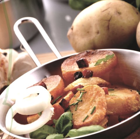 Bratkartoffeln und Zwiebeln in einer Pfanne.
, © Moses Ugo Nahaufnahme von knusprigen Kartoffelscheiben garniert mit Speckwürfeln, Schnittlauch und Zwiebeln in einer Pfanne neben weiteren Kartoffeln.