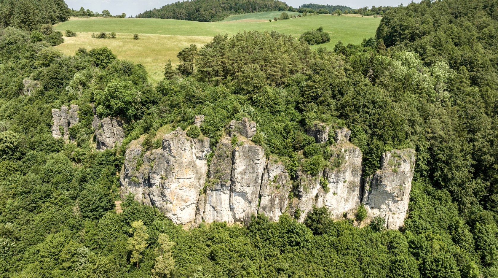 The Gerolsteiner Dolomites rock formation rises out of dense forests.
, © Eifel Tourismus GmbH, Dominik Ketz The Gerolsteiner Dolomites rock formation rises out of dense forests. Behind it lies a landscape of meadows.