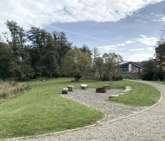 Spazierweg durch den Kurpark Stadtkyll mit Grillbereich
, © Touristik GmbH Gerolsteiner Land Barrierefreier Spazierweg durch den Kurpark Stadtkyll mit Grillschale und Steinen als Sitzgelegenheit. Gebäude im Hintergrund.