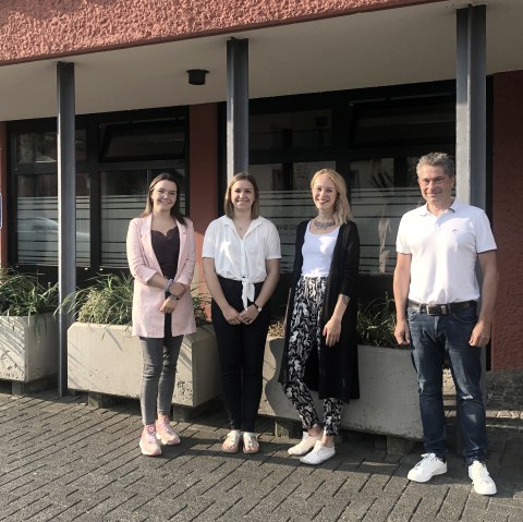 Begrüßung der neuen Mitarbeiterinnen der Touristik GmbH Gerolsteiner Land durch Geschäftsführer Frank Reuter.
, © Touristik GmbH Gerolsteiner Land Drei Frauen und ein Mann stehen nebeneinander vor einem Gebäude und lächeln in die Kamera.