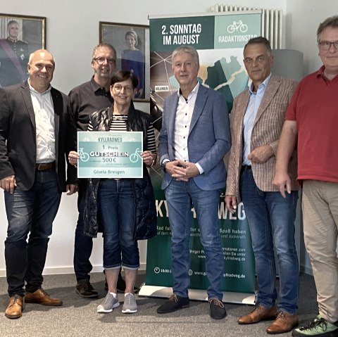 Preisverleihung Radaktionstag Grenzenlos Kyllradweg, v.l. Herr Hau (Westenergie), Herr Schmitz (Bürgermeister Stadtkyll), Frau Bresgen (Gewinnerin), Herr Wirtz (Bürgermeister Büllingen), Herr Westerburg (Bürgermeister Hellenthal), Herr Weicker (Bürgermeister Hallschlag), © Touristik GmbH Gerolsteiner Land Sechs Personen lächeln in die Kamera. Eine Frau hält einen großen Gutschein über 500 € in dne Händen.