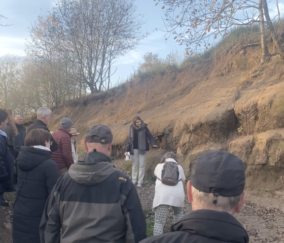 Personen bei einer Führung durch den Vulkangarten Steffeln.
, © Touristik GmbH Gerolsteiner Land Mehrere Personen bei einer Führung durch den Vulkangarten Steffeln vorbei an einer Erdschichtwand. Eine Frau erklärt den Gästen etwas.