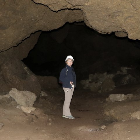Gästeführerin Brunhilde Rings inmitten der Birresborner Eishöhlen
, © Brunhilde Rings Eine Frau mit Helm und Taschenlampe einer großen Steinhöhle.