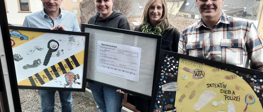 v.l.n.r.: Frank Reuter, Geschäftsführer Touristik GmbH Gerolsteiner Land, Jennifer Utecht, Leitung Integrative Kindertagesstätte Hillesheim, Steffi Götten, Leitung Kita Kunterbunt Hillesheim, Wolfgang Heck, 1. Vorsitzender Urlaubsregion Hillesheim, © Touristik GmbH Gerolsteiner Land 4 Personen stehen auf einem Balkon oberhalb einer Stadt. Sie halten 3 eingerahmte Bilder in den Händen. 2 der Bilder sind von Kindern gebastelte Collagen und das Bild in der Mitte zeigt einen Spendenscheck.