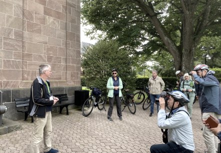 Pressetermin vor der Erlöserkirche, © Christina Ihrlich, RLP Tourismus Mehrere Personen vor einem Gebäude. Einige halten Kameras auf einen Mann gerichtet.