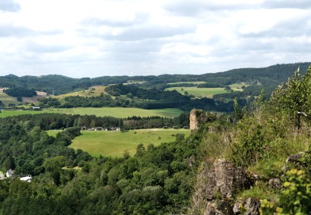 Dolomieten Gerolstein, © Janna Kamphaus Uitzicht op een heuvelachtig weide- en boslandschap met verspreid liggende huizen en windturbines ertussen. Rechts in beeld torenen rotsen uit.