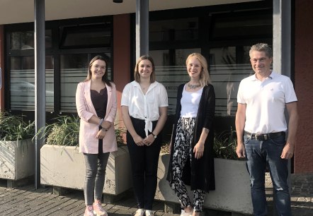 Managing Director Frank Reuter welcomes the new employees of Touristik GmbH Gerolsteiner Land.
, © Touristik GmbH Gerolsteiner Land Three women and one man stand next to each other in front of a building and smile for the camera.