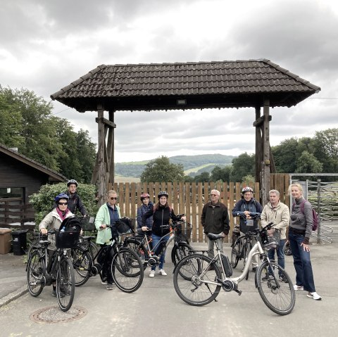 Mehrere Personen mit Fahrrädern vor dem Eingang des Adler- und Wolfspark Kasselburg.
, © Eifel Tourismus GmbH Neun sportlich gekleidete Personen stehen vor dem Eingang des Adler- und Wolfspark Kasselburg und einige Fahrrädern parken bei ihnen.