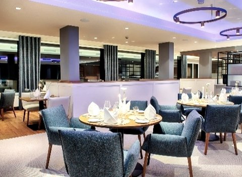 Modernes Restaurant im Seehotel am Stausee Gerolstein
, © Schinagl Modern eingerichteter Restaurantraum mit blauen Sofa-Stühlen an runden Tischen, die stilvoll gedeckt sind.