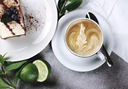 Coffee and cake in a restaurant
, © Pixabay Top view of a cup of coffee on a saucer with a spoon and a plate with a piece of cake next to it. Mint and limes are used as decoration.