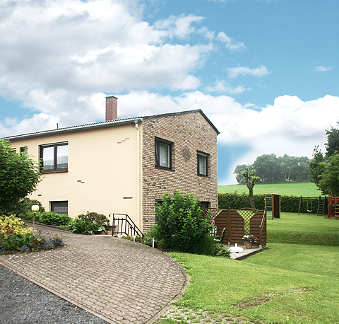 Vakantiewoning op Breitstein in Hillesheim
, © Familie Kremer Binnenplaatsingang van een woonhuis met enkele bomen en struiken bij het huis en een grote weide ernaast.