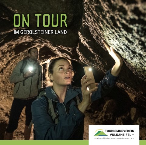 Cover page of the brochure ‘On Tour in Gerolsteiner Land., © Touristik GmbH Gerolsteiner Land Cover page of the brochure ‘On Tour in Gerolsteiner Land’ with a cover photo of two hikers in a dark cave.