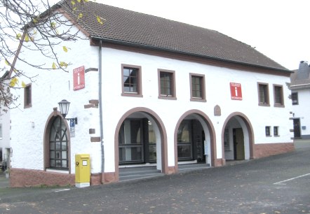 Außenfassade der Tourist-Information Stadtkyll., © Touristik GmbH Gerolsteiner Land Außenfassade der Tourist-Information Stadtkyll in der historischen Marktscheune mit Straße und Parkplatz davor.