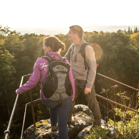 Zwei Personen stehen auf einem Felsen, umgeben von einem dichten Wald und schauen in die Ferne.
, © Eifel Tourismus GmbH, Dominik Ketz Zwei Personen stehen auf einem Felsen mit Blick auf einen Wald und Hügel im Hintergrund.