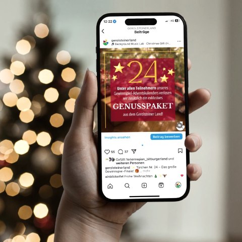 Social Media Adventskalender 2024, © Touristik GmbH Gerolsteiner Land Eine Hand hält ein Smartphone, worauf ein Instagram Beitrag für das 24. Türchen des Social Media Adventskalenders geöffnet ist.