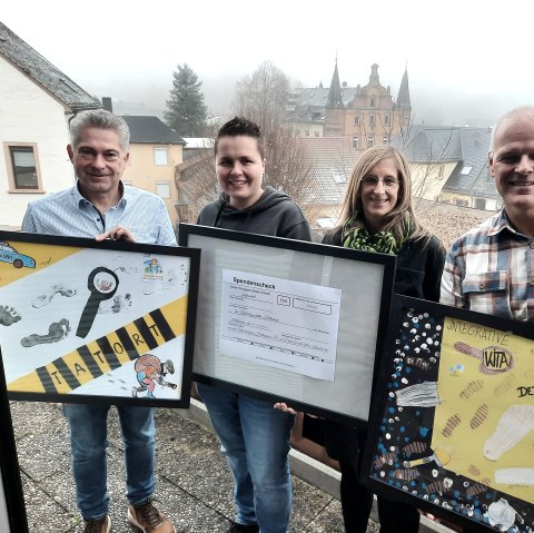 v.l.n.r.: Frank Reuter, Geschäftsführer Touristik GmbH Gerolsteiner Land, Jennifer Utecht, Leitung Integrative Kindertagesstätte Hillesheim, Steffi Götten, Leitung Kita Kunterbunt Hillesheim, Wolfgang Heck, 1. Vorsitzender Urlaubsregion Hillesheim, © Touristik GmbH Gerolsteiner Land 4 Personen stehen auf einem Balkon oberhalb einer Stadt. Sie halten 3 eingerahmte Bilder in den Händen. 2 der Bilder sind von Kindern gebastelte Collagen und das Bild in der Mitte zeigt einen Spendenscheck.