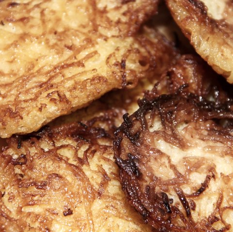 Fettig glänzende Reibekuchen.
, © Pixabay Nahaufnahme von mehreren gestapelten Kartoffel-Reibekuchen, die vom Fett glänzen.