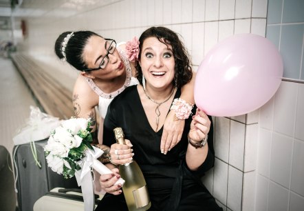 Das Kabarett-Duo "Weibsbilder"
, © Ralf Cornesse Zwei Frauen in schicker Kleidung posieren zusammen mit einer Flasche Sekt, Luftballon und einem Blumenstrauß in den Händen.