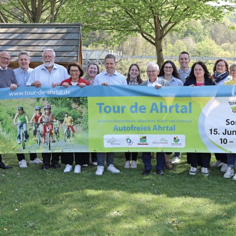 Pressefoto Tour de Ahrtal 2025
, © Thorsten Trütgen, VG Altenahr 16 Personen stehen dicht beieinander, halten ein Banner für den Radaktionstag Tour de Ahrtal am Sonntag, 15. Juni 2025 hoch und lächerln in die Kamera.