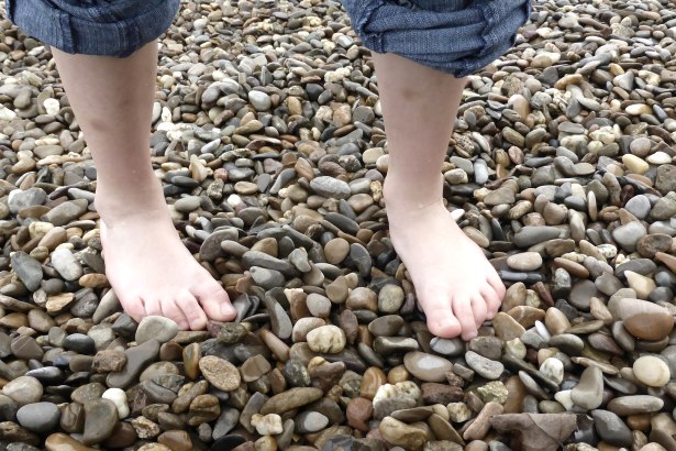 Two bare feet are standing on a pebble beach. The person is wearing rolled-up jeans., © pixabay Two bare feet are standing on a pebble beach. The person is wearing rolled-up jeans., © pixabay