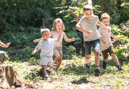 Vijf kinderen rennen vrolijk naast elkaar door een bos., © Canva Vijf kinderen rennen vrolijk naast elkaar door een bos.