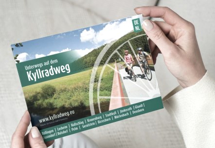 Titelseite Flyer "Unterwegs auf dem Kyllradweg"
, © Touristik GmbH Gerolsteiner Land Der Flyer "Unterwegs auf dem Kyllradweg" wird hochgehalten.