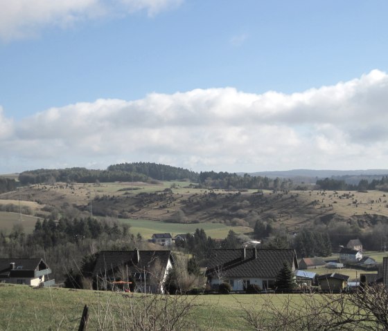 Landschap met groene heuvels, verspreide huizen en weilanden onder een blauwe lucht met wolken., © Touristik GmbH Gerolsteiner Land, Ute Klinkhammer Landschap met groene heuvels, verspreide huizen en weilanden onder een blauwe lucht met wolken., © Touristik GmbH Gerolsteiner Land, Ute Klinkhammer
