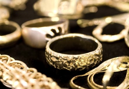 Goldschmuck Nahaufnahme
, © Canva Nahaufname mehrerer goldener Ringe, Armbänder und Ketten auf schwarzem Grund.