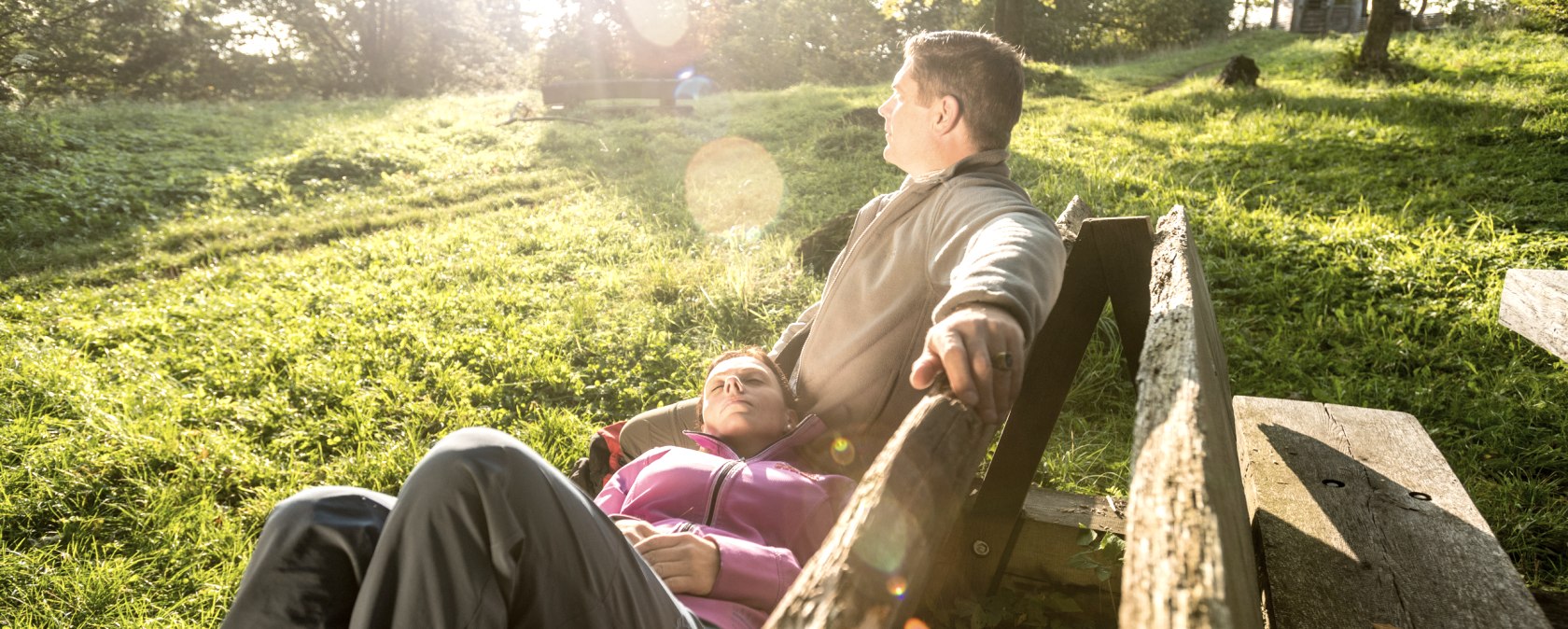 Relaxing break on the Gerolstein Celtic Trail
, © Eifel Tourismus GmbH, Dominik Ketz Two people relax on a bench in the sunshine on a meadow.