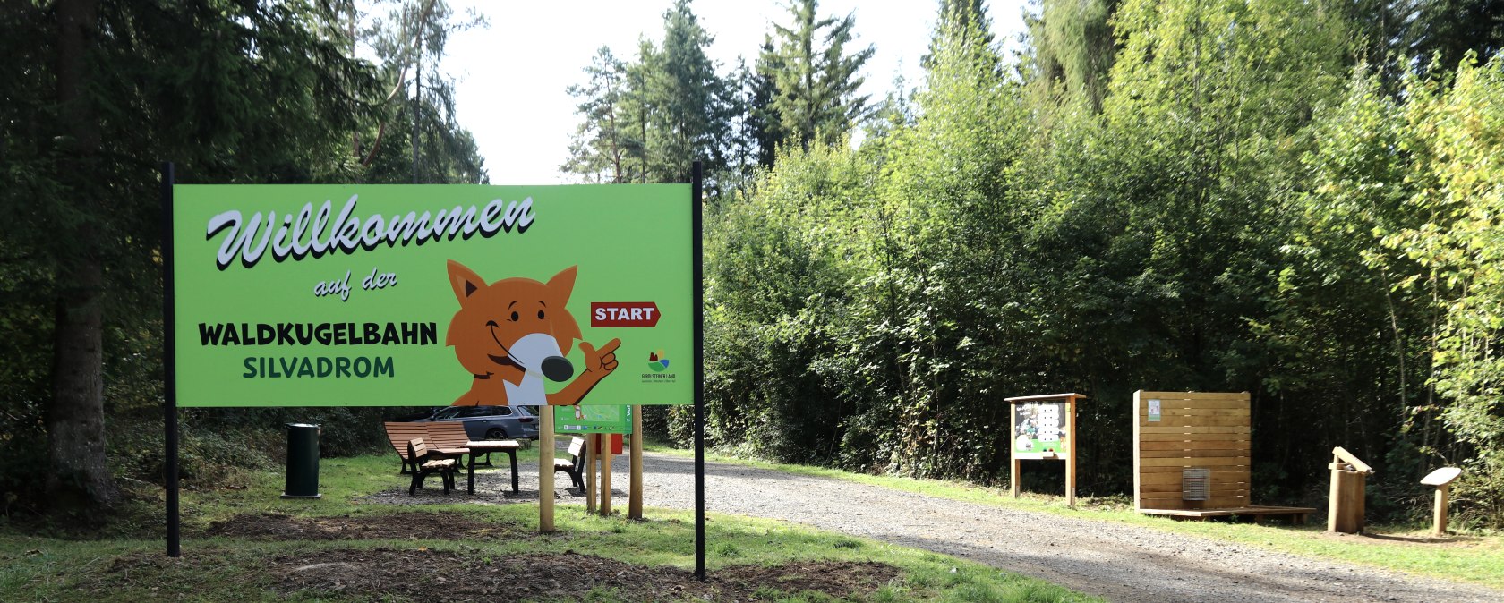 Eingang zum Naturerlebnispfad mit einem großen Schild der Waldkugelbahn Silvadrom. Ein Weg führt in den Wald, umgeben von Bäumen und Infotafeln., © Thomas Langens Eingang zum Naturerlebnispfad mit einem großen Schild der Waldkugelbahn Silvadrom. Ein Weg führt in den Wald, umgeben von Bäumen und Infotafeln., © Thomas Langens