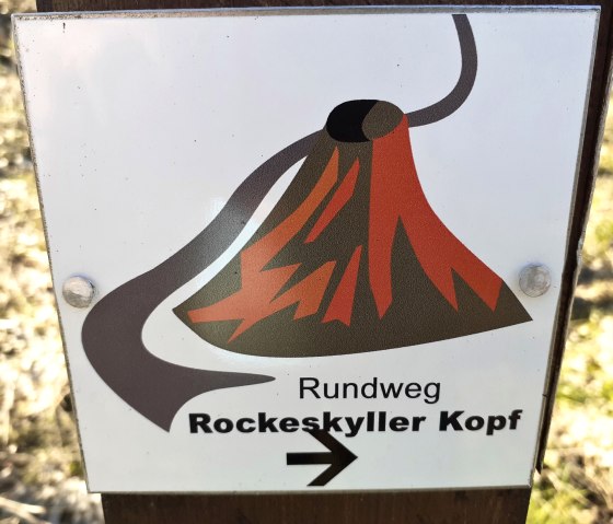 Bord met vulkansymbool en pijl, met het opschrift 'Rundweg Rockeskyller Kopf'., © Touristik GmbH Gerolsteiner Land, Ute Klinkhammer Bord met vulkansymbool en pijl, met het opschrift 'Rundweg Rockeskyller Kopf'., © Touristik GmbH Gerolsteiner Land, Ute Klinkhammer