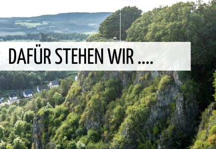 Die Gerolsteiner Dolomiten mit Schriftzug "Dafür stehen wir ...", © Touristik GmbH Gerolsteiner Land Mit Vegetation überwachsene Dolomitfelsen über der Stadt Gerolstein. Darüber ein eingerahmter Schriftzug "Dafür stehen wir ...".