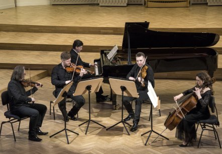 Christoph Soldan und die Schlesischen Kammersolisten beim musizieren
, © Soldan 4 Personen an Streichinstrumenten und ein Mann am Flügel musiziere gemeinsam auf einer Bühne.