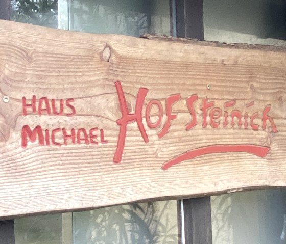 Holzschild mit Aufschrift "Haus Micheal Hof Steinich.
, © Touristik GmbH Gerolsteiner Land Holzschild mit Aufschrift "Haus Micheal Hof Steinich an einer Fensterscheibe.