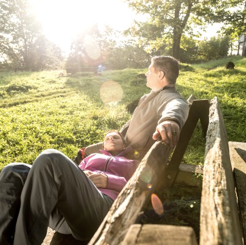 Entspannte Rast am Gerolsteiner Keltenpfad
, © Eifel Tourismus GmbH, Dominik Ketz Zwei Personen entspannen auf einer Bank im Sonnenschein auf einer Wiese.