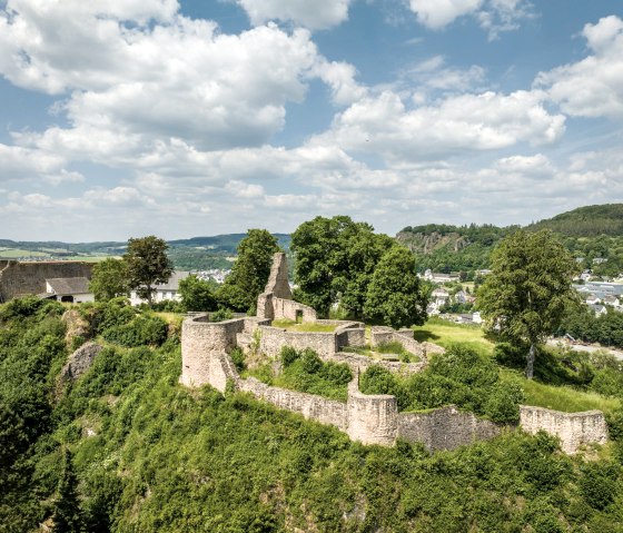 Ruinen der Löwenburg in Gerolstein, umgeben von grüner Landschaft und Bäumen, unter blauem Himmel mit Wolken., © Eifel Tourismus GmbH, Dominik Ketz Ruinen der Löwenburg in Gerolstein, umgeben von grüner Landschaft und Bäumen, unter blauem Himmel mit Wolken., © Eifel Tourismus GmbH, Dominik Ketz