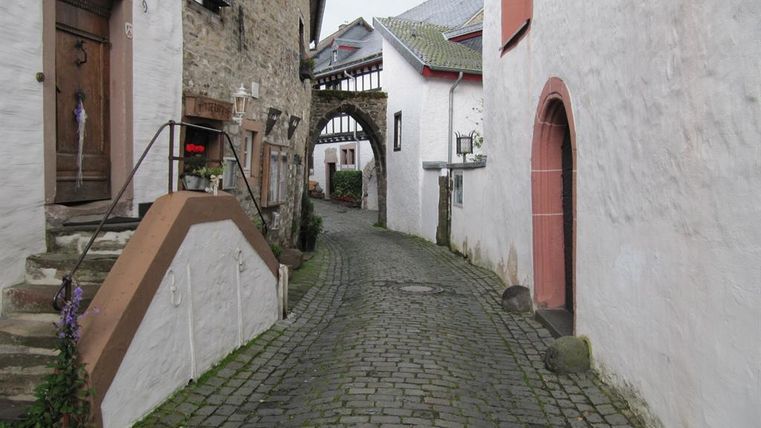 Eine enge, gepflasterte Gasse mit historischen Gebäuden. Die Atmosphäre ist gemütlich und typisch für eine malerische Stadt.