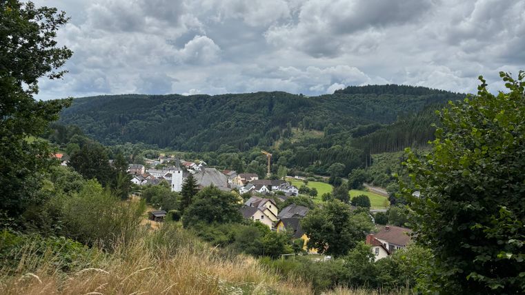 View of a village in a hilly landscape with a cloudy sky.