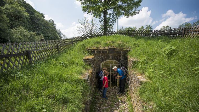 Personen vor dem durch eine Gittertür verschlossenen Quellbunker.