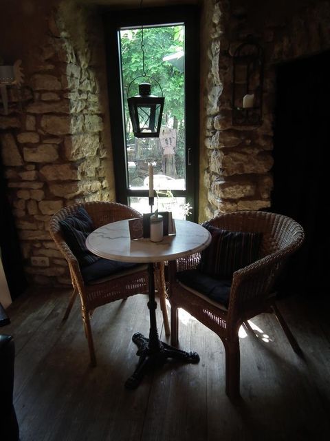 Gemütliche Sitzecke mit zwei Korbstühlen und einem runden Tisch vor einem Fenster in einem rustikalen Landcafé.