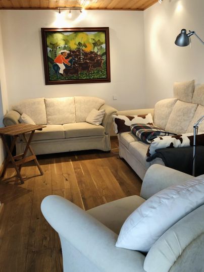 Een gezellige woonkamer met twee banken en een klein tafeltje. Aan de muur hangt een kleurrijk schilderij.