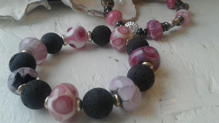Armband aus rosanen Glasperlen mit schwarzen Perlen.