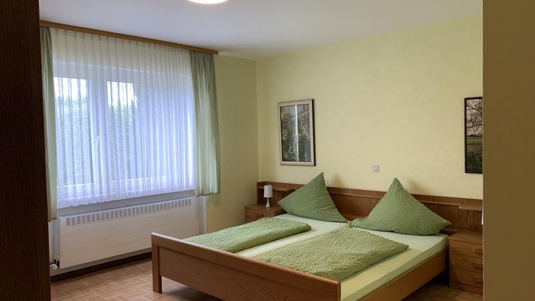 Ein gemütliches Schlafzimmer mit einem großen Doppelbett und zwei Kissen in grün. Das Zimmer hat viel Tageslicht und eine freundliche Atmosphäre.