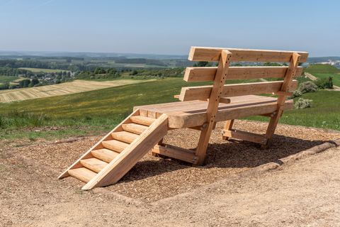 Überdimensionale Ruhebank vor weitläufiger Landschaft.